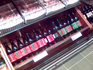 Flasker med Haandbryggeriets juleøl, liggende på skrå i Vinmonopolets nederste rekke med hyller.