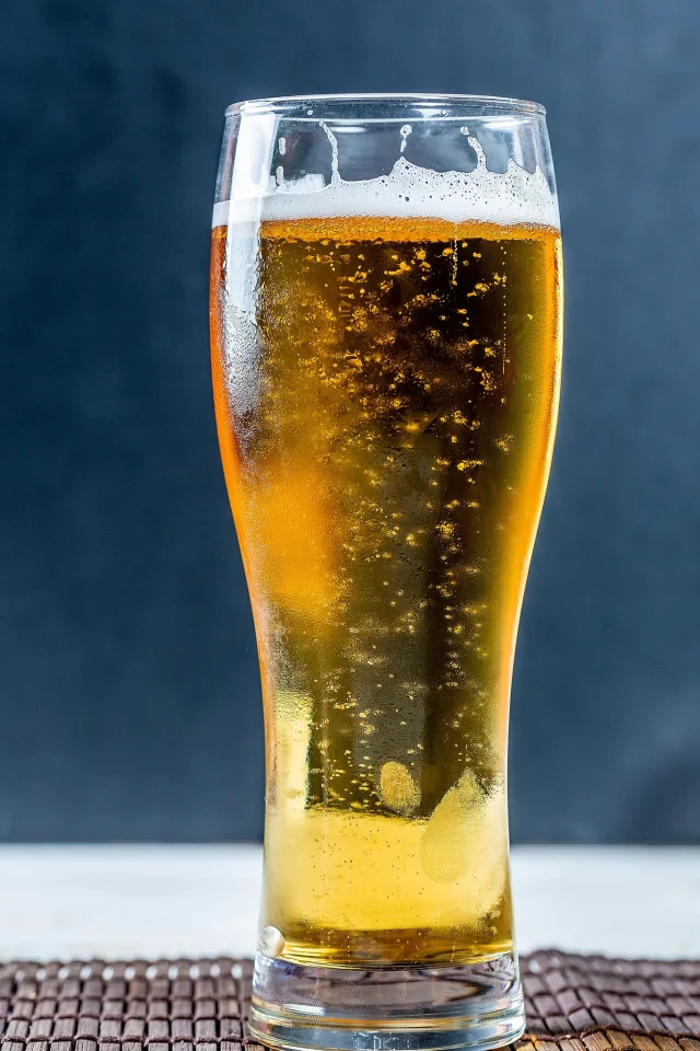 Et duggende, tradisjonelt pilsnerglass, fylt med kaldt øl